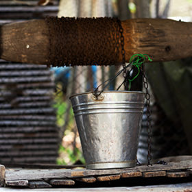 Closeup of a well with pulley and aluminium bucket