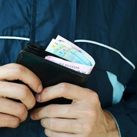 Man holds in hands black leather wallet with ukrainian money or thief who stole wallet full of money. Ukrainian economic crisis and crime concept