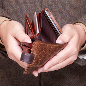 Broke businessman showing brown leather empty wallet. Business concept- finance and poor economy.