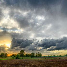 Colorful countryside sunrise or sunset over the agraric farmfields showing the dramatic colors and stormy clouds in the dark sky