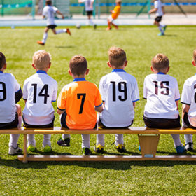 Young Football Players. Young Soccer Team Sitting on Wooden Bench. Soccer Match For Children. Young Boys Playing Tournament Soccer Match. Youth Soccer Club Footballers