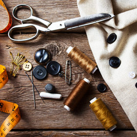 Sewing accessories: scissors, needle, thimble on wooden table