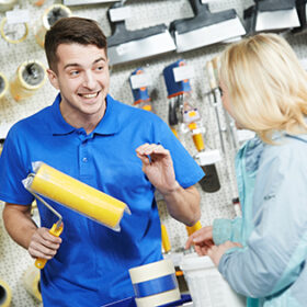 Assistant seller help buyer by demonstrating paint roller for painting at hardware store