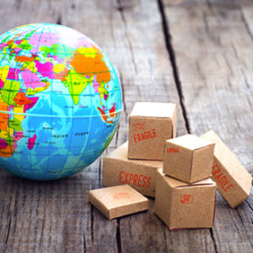 Miniature globe and boxes on wooden background
