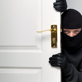 Home burglary concept with a burglar sneaking in a open house door