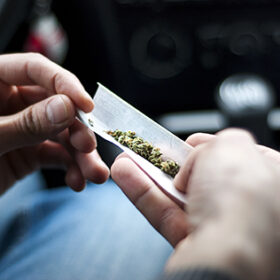 Man making joint and a stash of marijuana in the car
