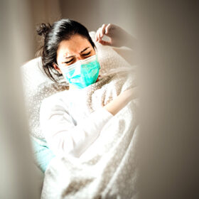 Sick woman with mask in mobile quarantine hospital units isolation.Coronavirus Covid-19 patient having pneumonia disease symptoms health care treatment.Painful cough.Lung disease.Antitussic drug help