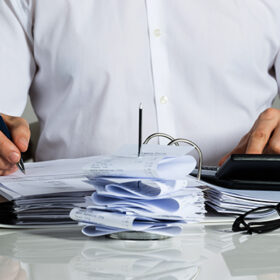 Midsection of businessman calculating invoice at office desk
