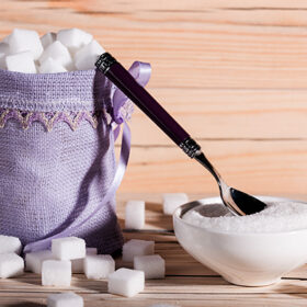 White sugar cubes in a bag on wooden background