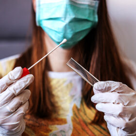 Close up of young woman with sample swab. Selective focus on sample. Corona virus protective measures.