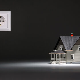 Home architectural model with socket on grey background