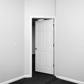black and white image of an empty room with door opening out