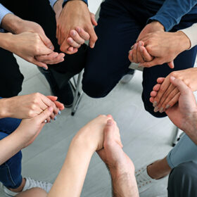 Hands of people supporting each other at group psychotherapy session
