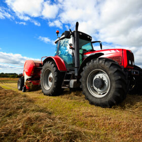 huge tractor collecting haystack in the field in a nice blue sunny day