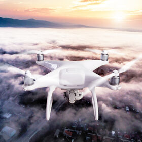 Hovering drone taking pictures of mornig town covered by mist. Hills. Sun rising. Netherlands. Aerial view.