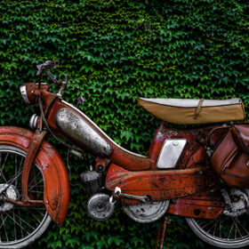 Vintage 60s French Moped Or Scooter With Pannier Bag And Flat Tyre Or Scooter Against An Ivy Background