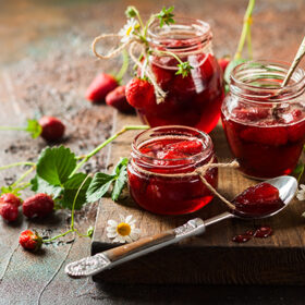 Homemade strawberry jam in glass jars on wooden board in rustic style. Healthy food for breakfast