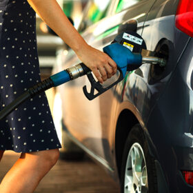 Woman fills petrol into her car at a gas station