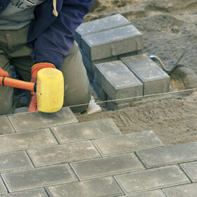 The worker lay the paving slab with special hammers, leveling it according to the level of the tensioned thread