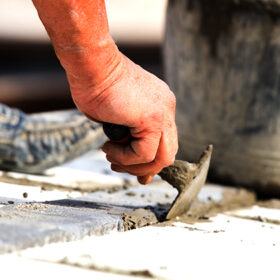 Construction worker working hard and leveling concrete pavement outdoors.