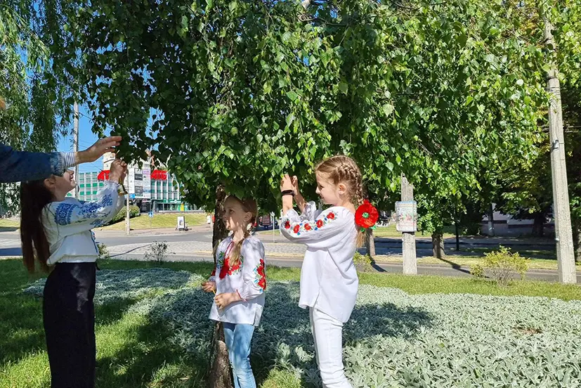 діти прив’язують дзвіночки на дерева