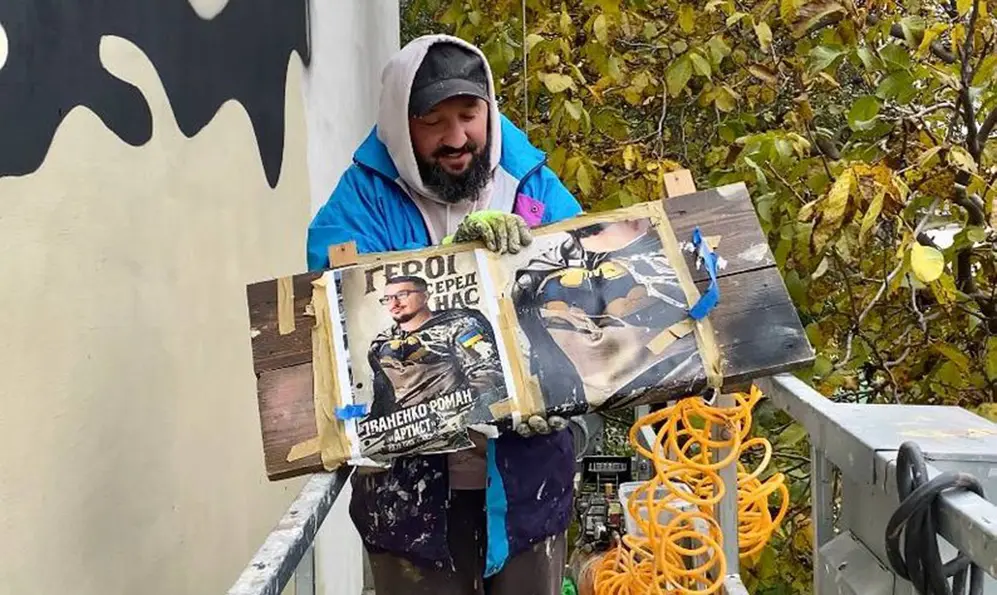 Художник-монументаліст Віталій Фісун, показує ескіз муралу на честь Романа Іваненка, який розробляли з дитячого малюнка. Фото: Леся Продоус